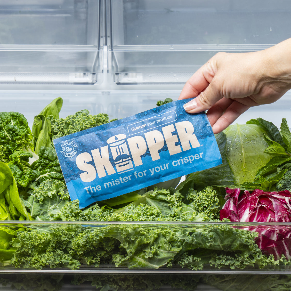 A hand placing a Skipper into a bed of fresh vegetables.